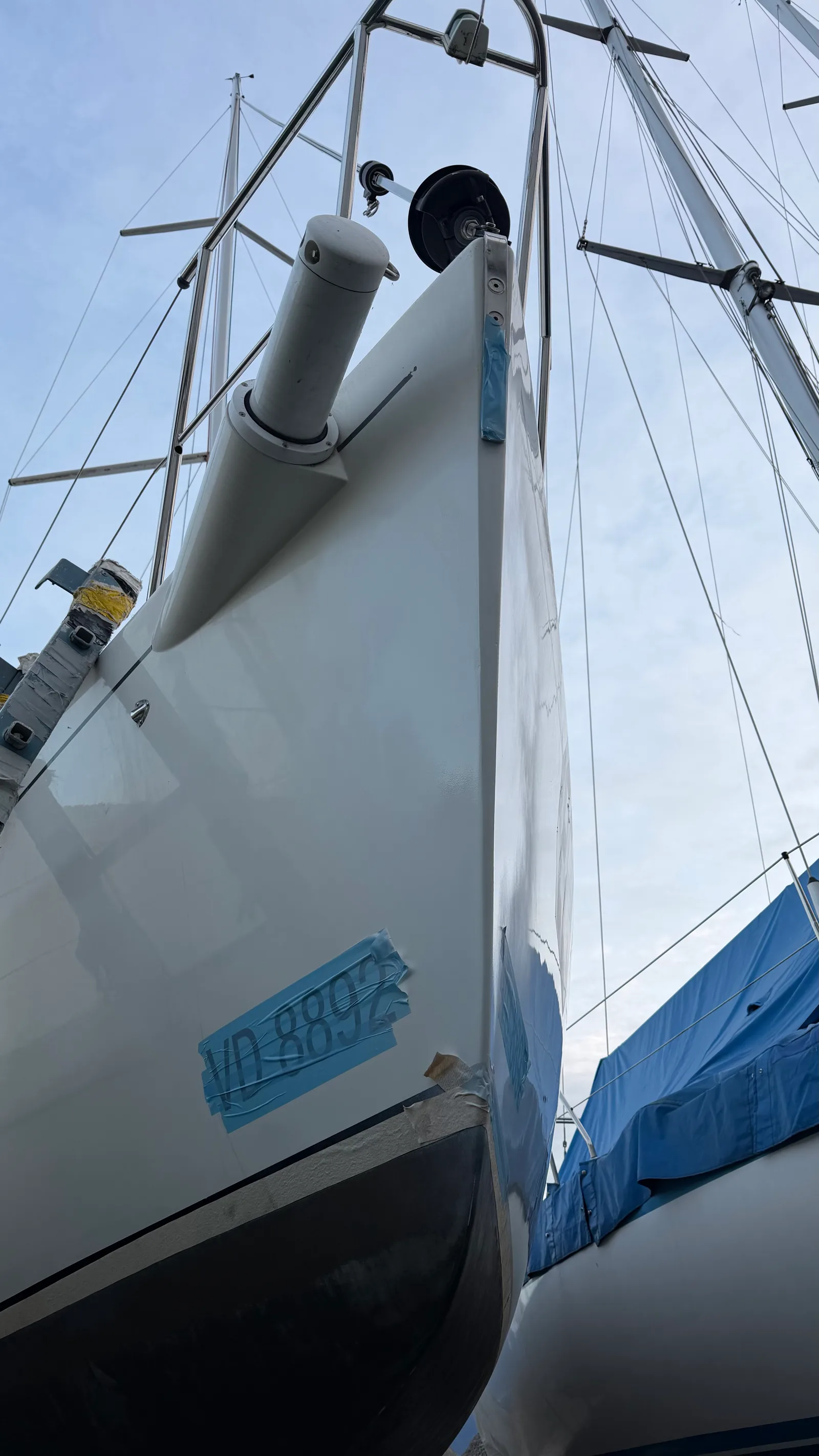 Étrave d'un J/92s au sec : écailles de gelcoat manquantes le long de la ligne d'étrave, dégâts cosmétiques typiques d'un bateau qui a régaté