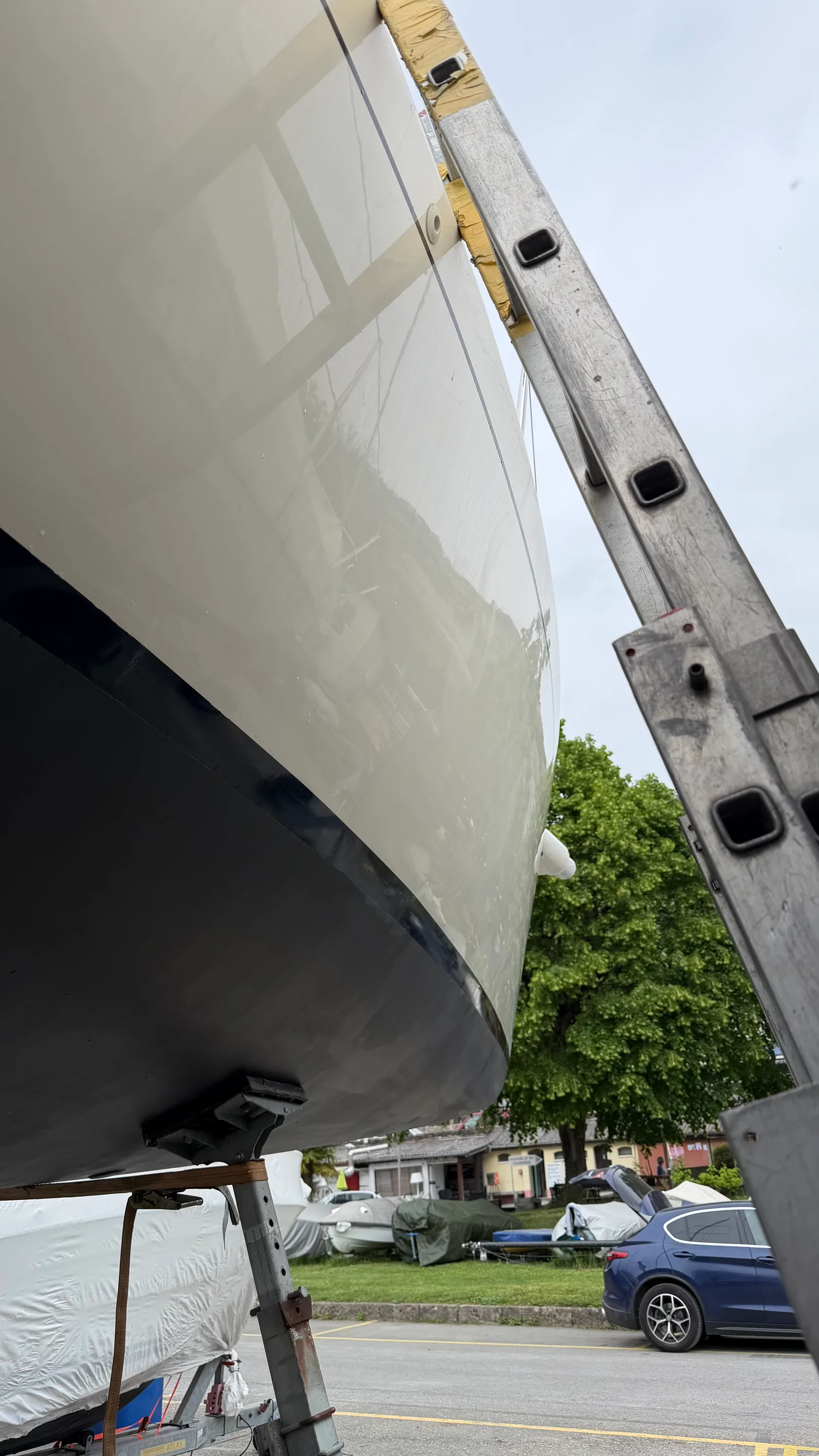 Ponçage à l'orbitale sur le bordé bâbord d'un J/92s : passage successif au grain fin pour aplanir le gelcoat repris sans creuser la matière