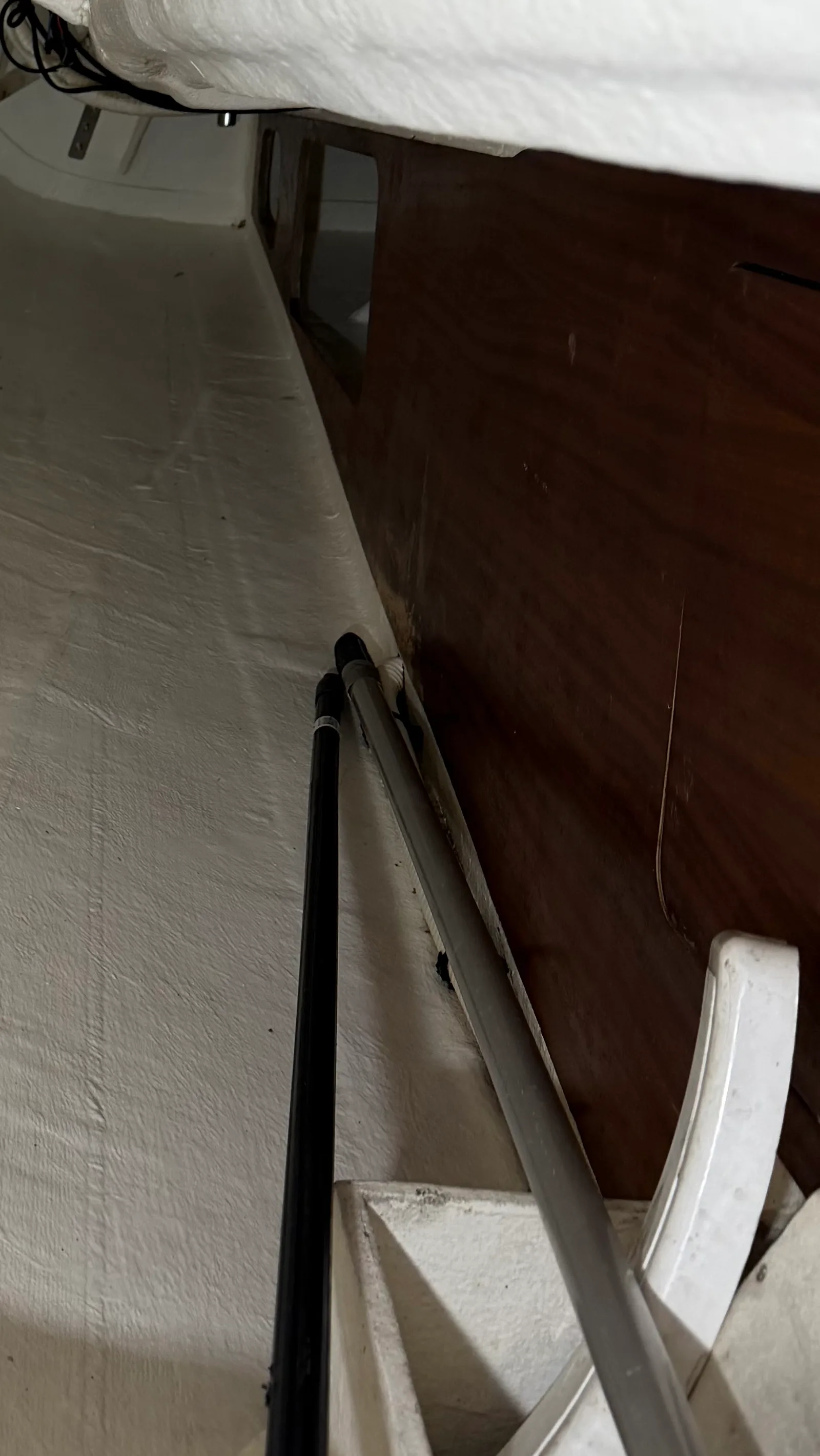Avant refit : cloison bois tribord du compartiment moteur avec finition abîmée par l'humidité — zone sombre en bas à droite où le vernis a lâché et le contreplaqué a bu l'eau
