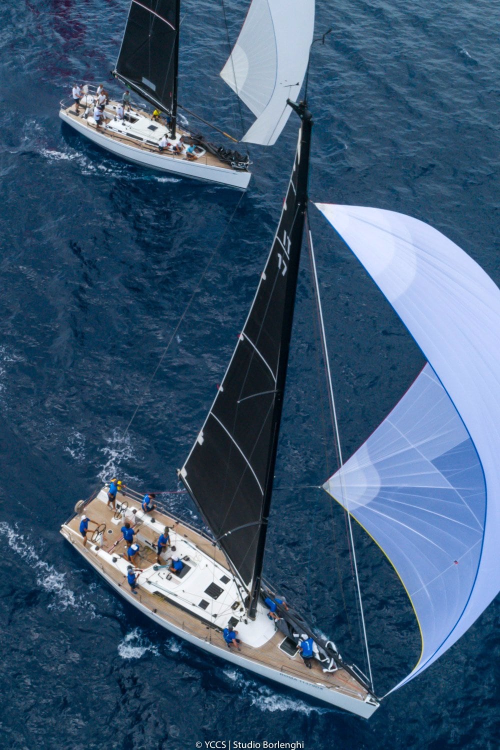 Maxi yachts en course au large sous spinnaker vus du ciel — voiliers de régate en Méditerranée.